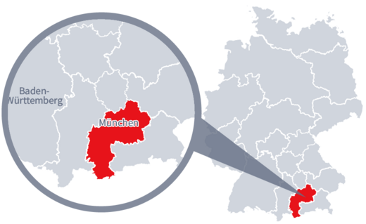 Diese Grafik zeigt eine Karte von Deutschland mit einer detaillierten Ansicht der Region München. München ist in Rot hervorgehoben und liegt im südlichen Teil Deutschlands. Ein Lupensymbol vergrößert diesen Bereich, um die Lage genauer darzustellen. 